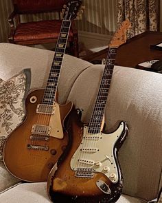 two guitars sitting on top of a couch