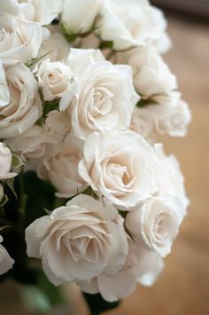 a bouquet of white roses sitting on top of a wooden table