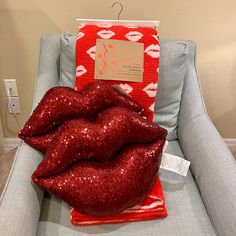 two shiny red lips sitting on top of a blue chair next to a package of lipstick