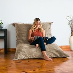 a woman sitting on a bean bag chair reading a book