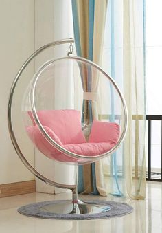 a hanging chair with pink cushions in front of a window and curtained curtains behind it