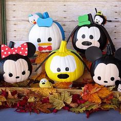 mickey mouse pumpkins and other decorations are on display in front of a wooden wall