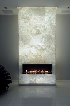 a modern fireplace in the middle of a living room with white walls and flooring