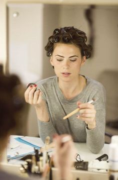 a woman is doing makeup in front of a mirror