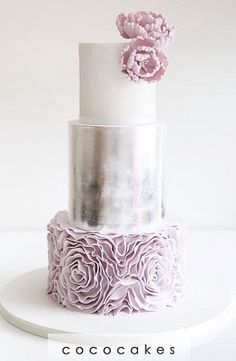 a three tiered cake with pink flowers on top