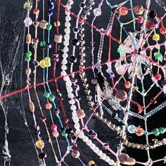 a bunch of necklaces that are hanging on a wall in front of a black background