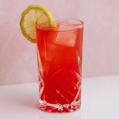 a red drink with a lemon slice on the rim