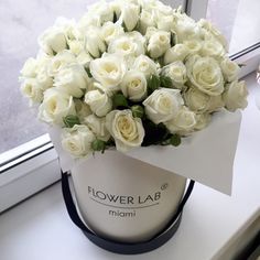 a bouquet of white roses sitting on top of a table next to a window sill