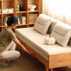 a woman kneeling down next to a white couch