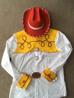 a white shirt with yellow and red designs on the collar has a cowboy hat attached to it