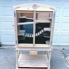 a white bird cage sitting on top of a wooden shelf next to a garage door