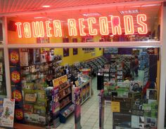 the inside of a record store with neon signs on the front and back windows that read tower records