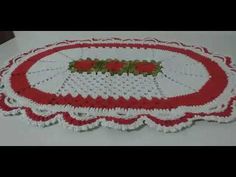 a crocheted tablecloth with red and white trimmings on the edge