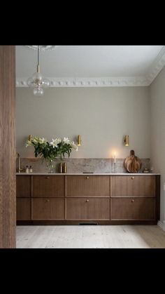 a bathroom with wooden cabinets and white flowers in vases on the sink counter top