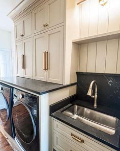 a washer and dryer in a kitchen with white cabinets on the wall behind them