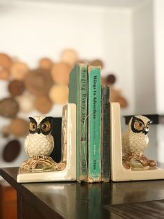 an owl figurine sitting on top of a book shelf next to two books