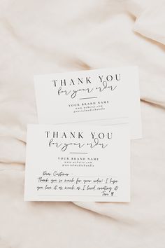 two thank you cards sitting on top of a white sheet with black ink that reads, thank you