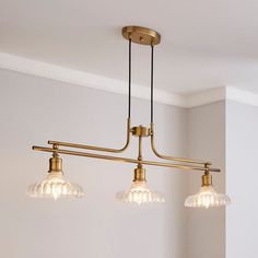 three lights hanging from a ceiling fixture in a room with white walls and flooring