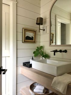 a bathroom sink sitting under a mirror next to a wooden shelf with towels on it