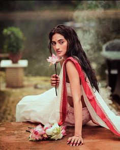 a woman kneeling down with a flower in her hand