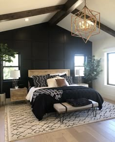 a bedroom with black walls and white bedding has a chandelier hanging from the ceiling