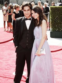 a young man and woman in formal wear on the red carpet