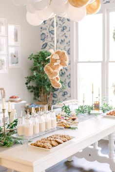 a teddy bear hanging from the ceiling over a table with desserts and drinks on it