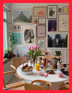 a dining room table with chairs and pictures on the wall in front of it's windows