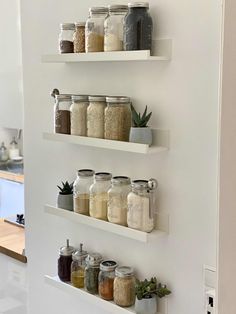 three white shelves filled with jars and spices