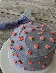 a cake with pink frosting roses on it sitting on a plate next to a bouquet of flowers