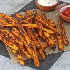 french fries with ketchup and dip on a tray next to some dipping sauce