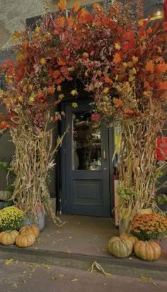 an entrance to a store with pumpkins and flowers