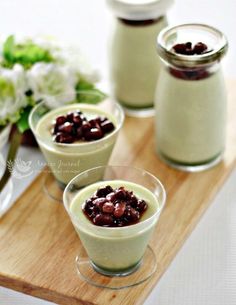 three glasses filled with pudding sitting on top of a wooden tray