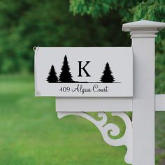 a white mailbox sitting on the side of a green grass covered field with trees