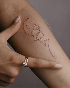 a woman's arm with a tattoo on it that has two faces and a crescent