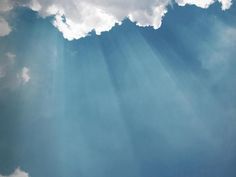 an airplane flying in the sky with sunbeams and clouds