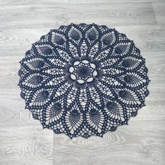 a black doily is on the floor with white wood grained floors in the background