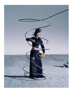 a woman standing on top of a sandy beach next to an object in the air