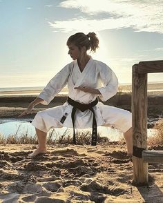 a woman is practicing karate on the beach