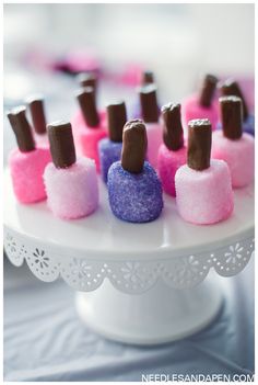 small marshmallows are arranged on a white cake platter with pink and purple icing