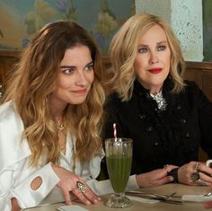 two women sitting at a table with drinks