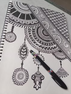 a pen sitting on top of a white paper covered in black and white paisley designs