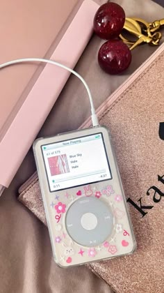 an ipod sitting on top of a bed next to a pair of gold headphones