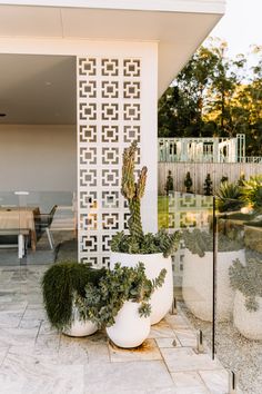 two large white planters sitting next to each other on a tiled floor near a table and chairs