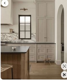 a kitchen with white cabinets and marble counter tops