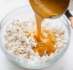 someone pouring caramel sauce on popcorn in a bowl