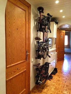 there are many bicycles mounted to the wall in this hallway with wooden floors and doors