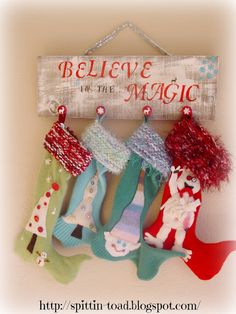 a sign that says believe in the magic with stockings hanging from it's hooks