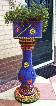 a colorful flower pot sitting on top of a sidewalk