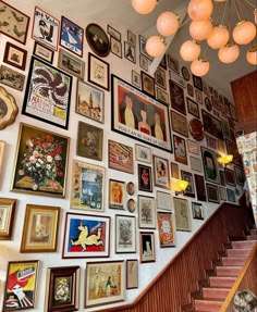 a staircase with many framed pictures on the wall next to it and a chandelier hanging from the ceiling